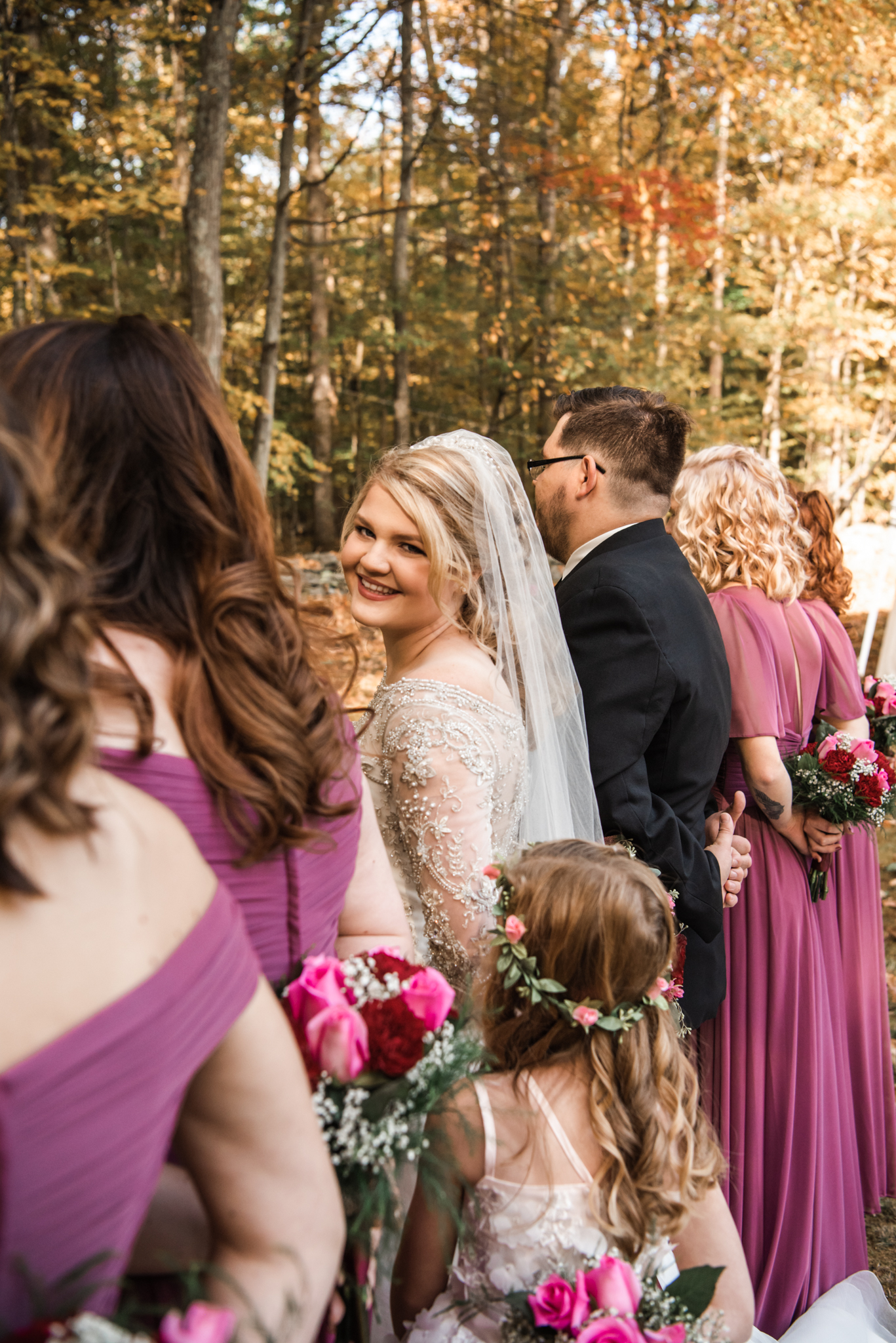 Sarah is posed in a wedding photo with her bridal party. She faces the camera while the rest are looking forward.